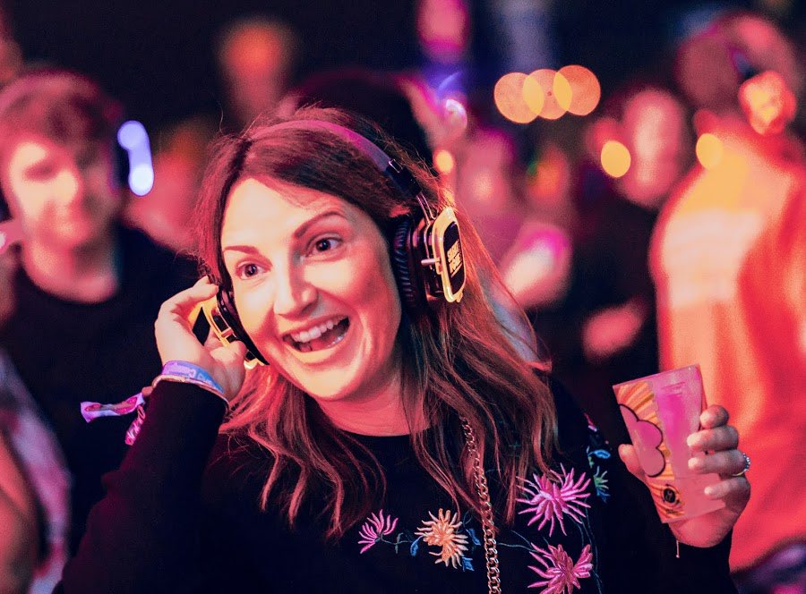 A lady listening to her headphones at a party
