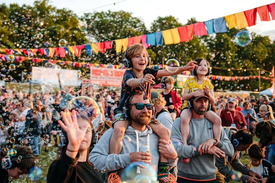 Kids on their dad shoulders at a silent disco festival