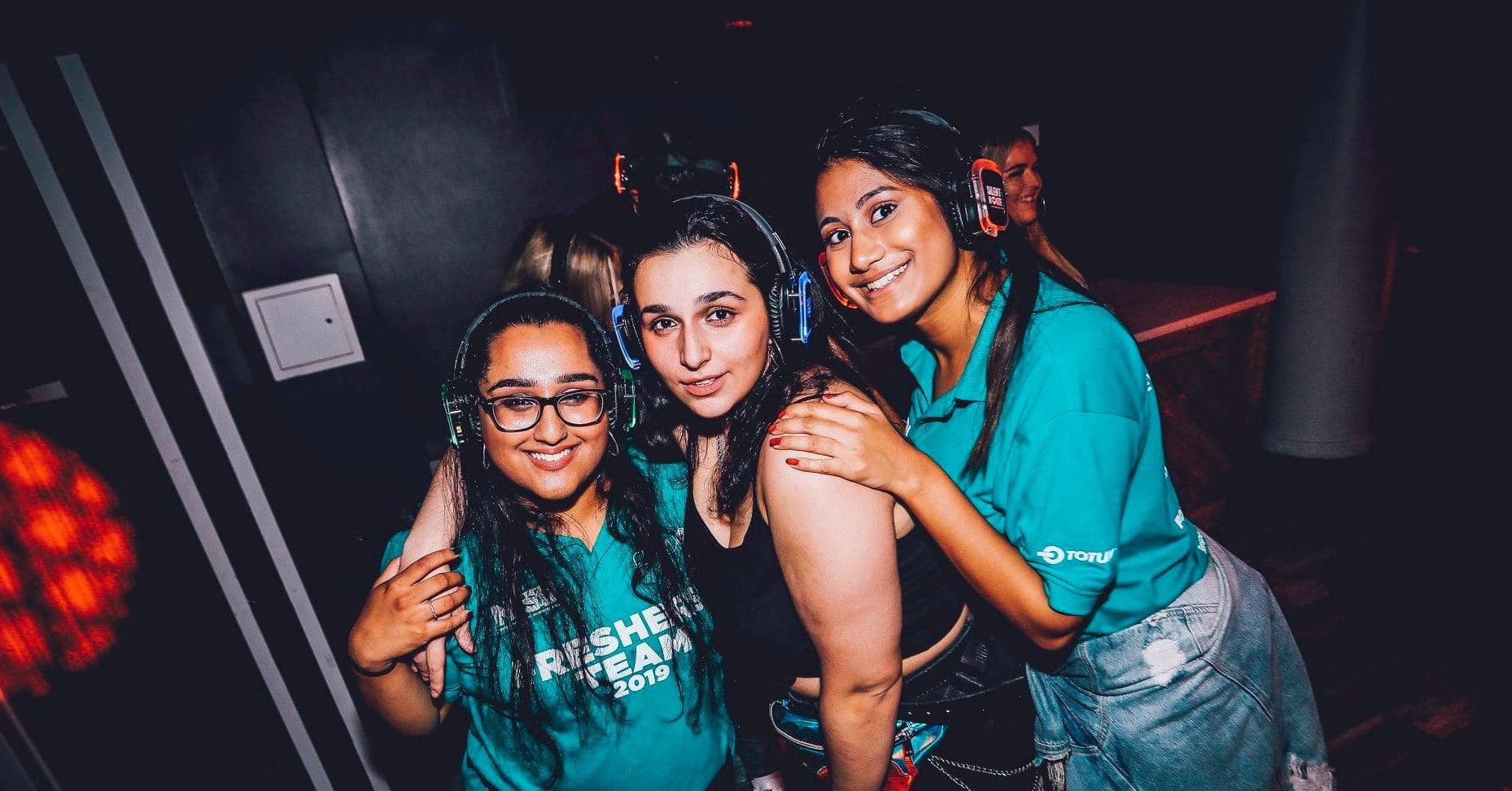 Three girls with silent disco headphones on